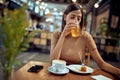 Lovely young woman sitting alone in coffee shop enjoying her juice and piece of cake Royalty Free Stock Photo