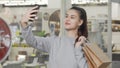 Lovely young woman taking selfies with her smart phone at the shopping mall