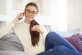 Lovely young woman talking with somebody on her mobile phone while sitting on sofa at home Royalty Free Stock Photo