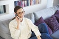 Lovely young woman talking with somebody on her mobile phone while sitting on sofa at home Royalty Free Stock Photo