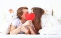 Lover couple kissing with a red heart in bed Royalty Free Stock Photo