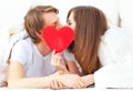 Lover couple kissing with a red heart in bed