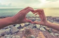 Lover hands in the form of heart against the sky with silhouette background.