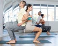 Lovers of active lifestyle perform pair yoga back to back chair pose in gym Royalty Free Stock Photo