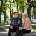 Lovers boy and girl look at each other, sitting in the Park near the fountain in the fall. Girlfriend and Boyfriend are talking Royalty Free Stock Photo