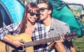 Lovers couple having fun outdoor cheering at camping place with vintage guitar - Young people enjoying summer time together Royalty Free Stock Photo