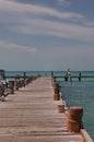 A couple of tourists jump into the sea from the old wooden pier, Caribbean ocean, Mexico, Cancun