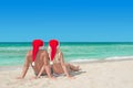 Lovers couple in red santa hats relaxing at tropical sandy beach Royalty Free Stock Photo