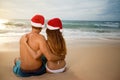 Lovers couple in Santa hats relaxing at sandy beach Royalty Free Stock Photo
