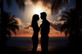 Lovers embrace, silhouetted against a sunset with palm trees Royalty Free Stock Photo