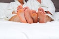 Lovers feet of a couple in love in a bed with white linens