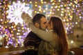 Lovers kiss on the background of shining festive garlands.