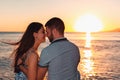 Lovers. Portraits of woman and man posing against the sea, sitting on the rocks in an embrace. Rear view. Sunset Royalty Free Stock Photo
