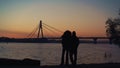 Lovers silhouette watching sunset at river shore. Beautiful evening clear sky. Royalty Free Stock Photo