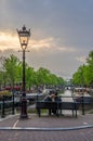 Lovers sit together at twilight overlooking a canal in Amsterdam