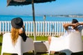Lovers sitting, looking into sky and sea, mountion, under sun umbrella. Vacation, tourism, hooneymoon. Girl with a long hair Royalty Free Stock Photo