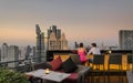 Lovers in a Twilight dining hour at an uncovered skyscraper`s terrace in Bangkok, Thailand.