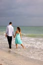 Lovers walking hand in hand along the beach in flo