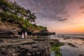 Lovers are watching flock of bats from cave on coastline at sunset