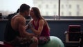 Lovers work out together. Woman giving her man kisses while doing press exercises. He helps her. Working out in the gym.