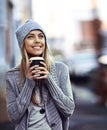 She loves city life. a beautful young woman standing with a takeaway coffee in the city.