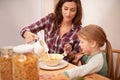 She loves her cereal. a woman pouring milk over her daughters cereal at breakfast time. Royalty Free Stock Photo