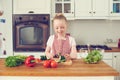 She loves making salads. Cute little girl making a salad at home in the kitchen.