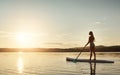 She loves the peace paddling gives her. an attractive young woman paddle boarding on a lake. Royalty Free Stock Photo