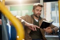 He loves to read while hes on the bus. a handsome young man reading a book during his morning bus commute. Royalty Free Stock Photo