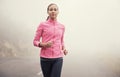 She loves to run alone. A young woman jogging on a country road on a misty morning. Royalty Free Stock Photo