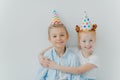 Lovey red haird girl embraces with love her older brother, congratulates with birthday, wear cone party hats, have good mood on