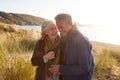 Loving Active Senior Couple Arm In Arm Walking Through Sand Dunes Royalty Free Stock Photo