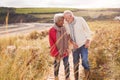 Loving Active Senior Couple Walking Arm In Arm Through Sand Dunes On Winter Beach Vacation Royalty Free Stock Photo