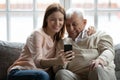 Loving adult granddaughter taking selfie on phone hugging senior grandfather