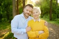 Loving adult son tenderly embracing elderly mother during walking at summer park. Two generations of family. Meeting of mom and Royalty Free Stock Photo