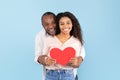 Loving african american couple celebrating their love, black middle aged man and young woman holding big red heart Royalty Free Stock Photo