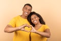 Loving african american couple cuddling and making together heart shape gesture with their hands as a sign of their love