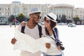 Loving african-american couple traveling and reading map in city