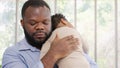 Loving African American dad embracing baby and baby girl sleeping on stepfather shoulder. Happy family with pleasure spending time