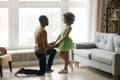 Loving African American father holding adorable preschool daughter hands