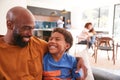 Loving African American Father And Son Sitting On Sofa At Home Together