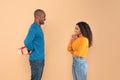 Loving african american man holding wrapped gift box, hiding present for his young wife behind back, side view Royalty Free Stock Photo