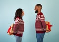 Loving african american man and woman holding Christmas presents behind their backs, exchanging gifts, blue background Royalty Free Stock Photo