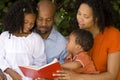 Loving African American parents reading with their kids. Royalty Free Stock Photo