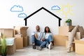 Loving african american spouses relocating to their home, dreaming about renovation, sitting near wall with drawn house