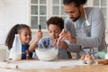 Loving African dad teach kids cooking in kitchen