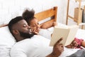 Loving african father reading fairy tales to his small daughter Royalty Free Stock Photo