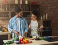 Loving afro american couple preparing green salad in kitchen