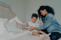 Loving afro american mother tickling son while having fun together in bedroom Royalty Free Stock Photo