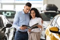 Loving arab couple checking booklet in car salon